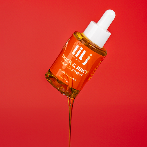 A dropper bottle of 'Thick & Juicy Hair Treatment' with a clear orange liquid visible inside, against a red background.